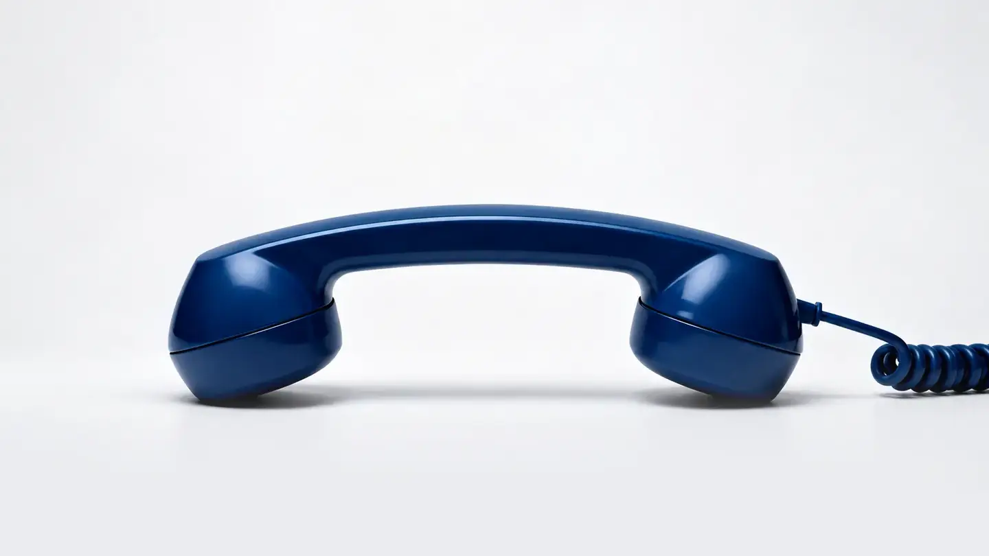 Contact Us — a navy telephone handset on a pale studio background