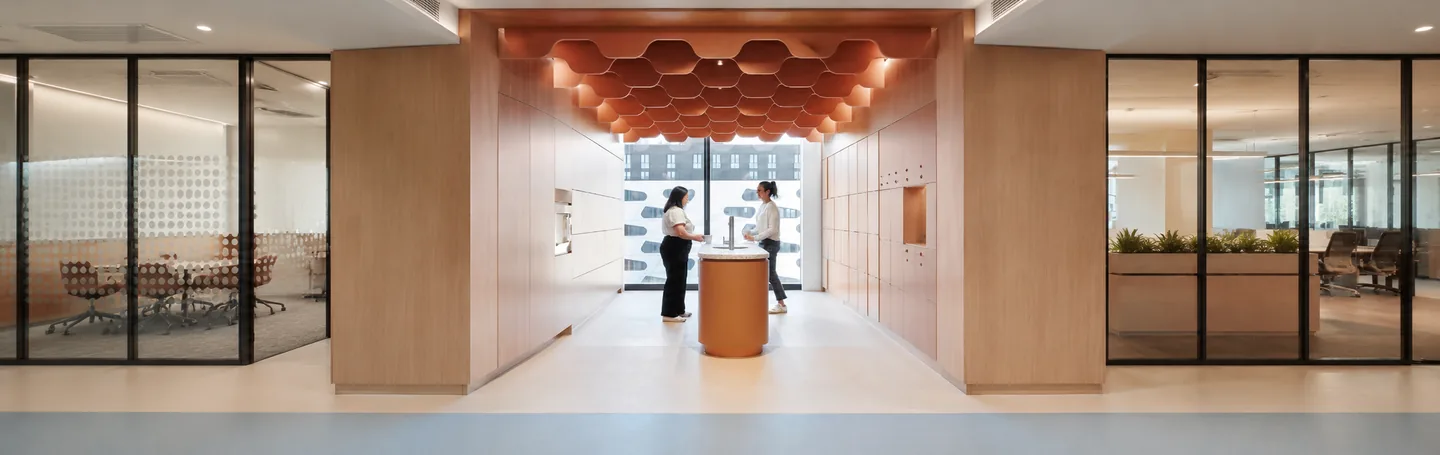 Office reception with a terracotta honeycomb acoustic ceiling above a circular welcome desk