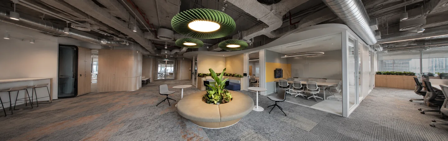 Green disc acoustic pendants above a circular planted seating island